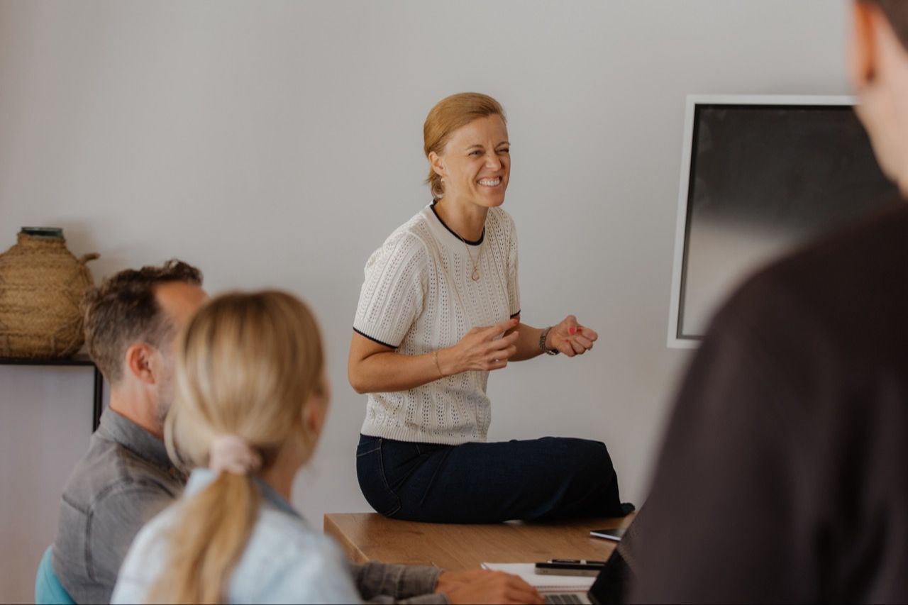 Elena laughing with a small group of participants around a table